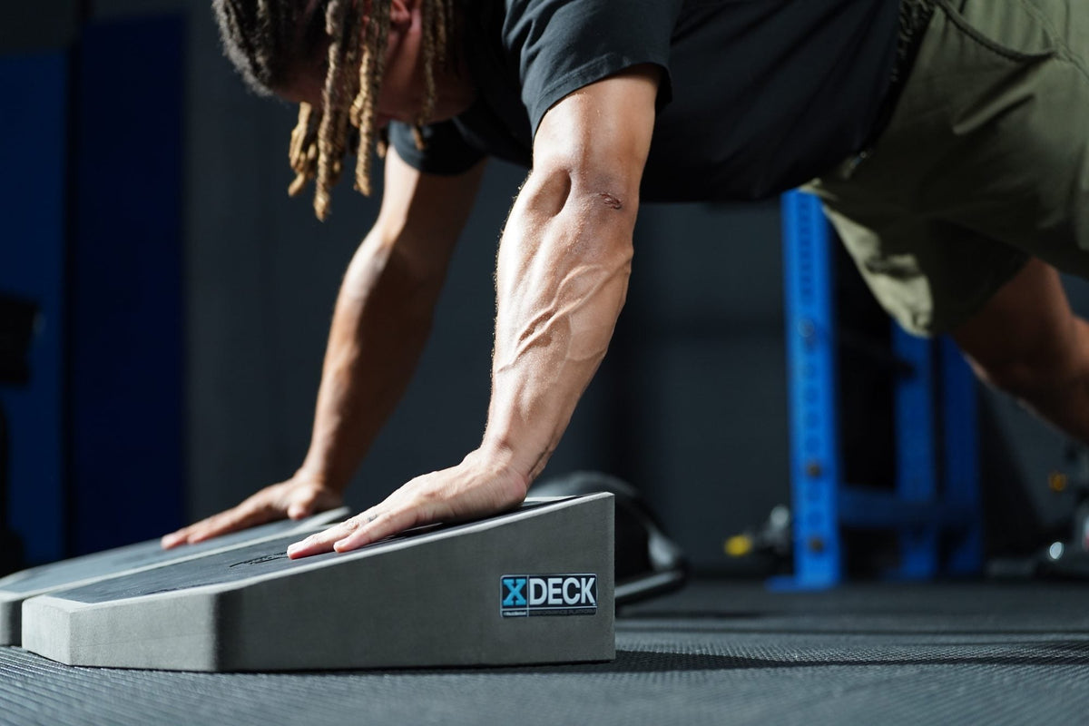 Athlete performing a push-up with hands on the XDECK platform